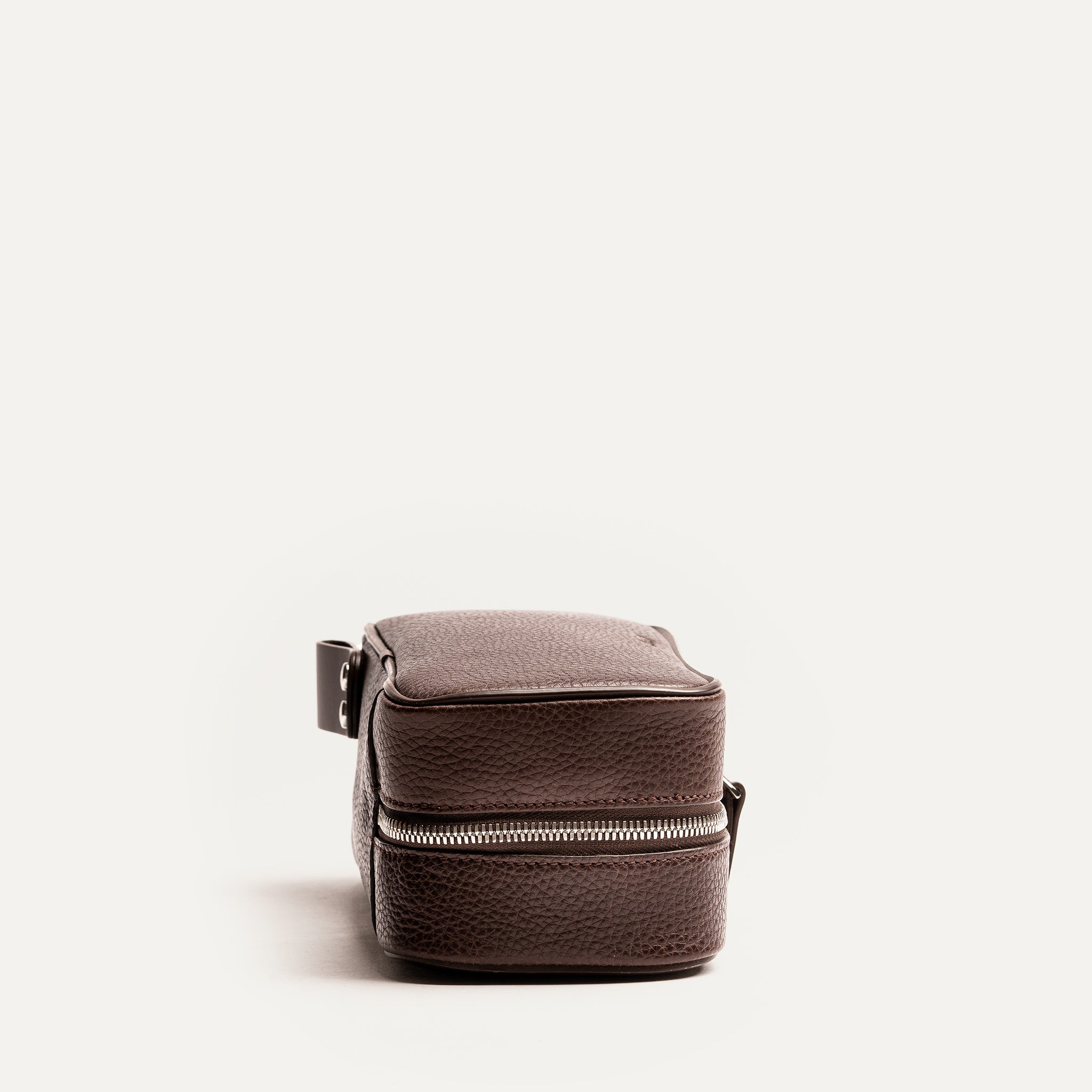 Trousse de toilette femme grand format vue de côté, en cuir marron grainé avec fermeture éclair solide.
