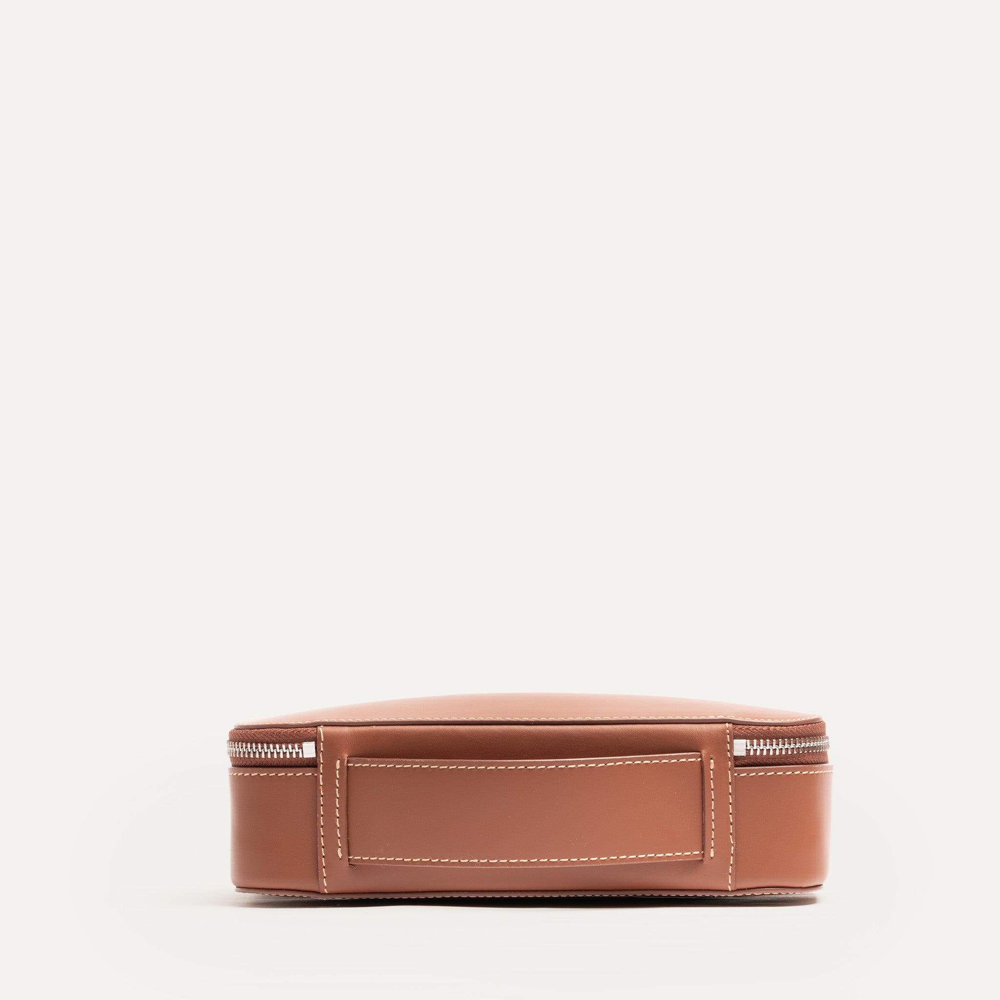 Vue arrière avec poignée intégrée d'une trousse de toilette pensé par lundi en cuir cognac.