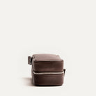 Trousse de toilette femme grand format vue de côté, en cuir marron grainé avec fermeture éclair solide.