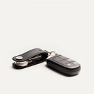 Porte clé en cuir avec clé de voiture attachée, posé incliné montrant une vue latérale du produit.