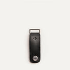 Porte clé personnalisé en cuir noir avec finition métal, posé à plat sur fond clair, vu de face.