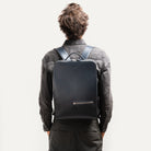 sac à dos homme en cuir porté avec un costume, parfait pour travailler avec un style business chic.