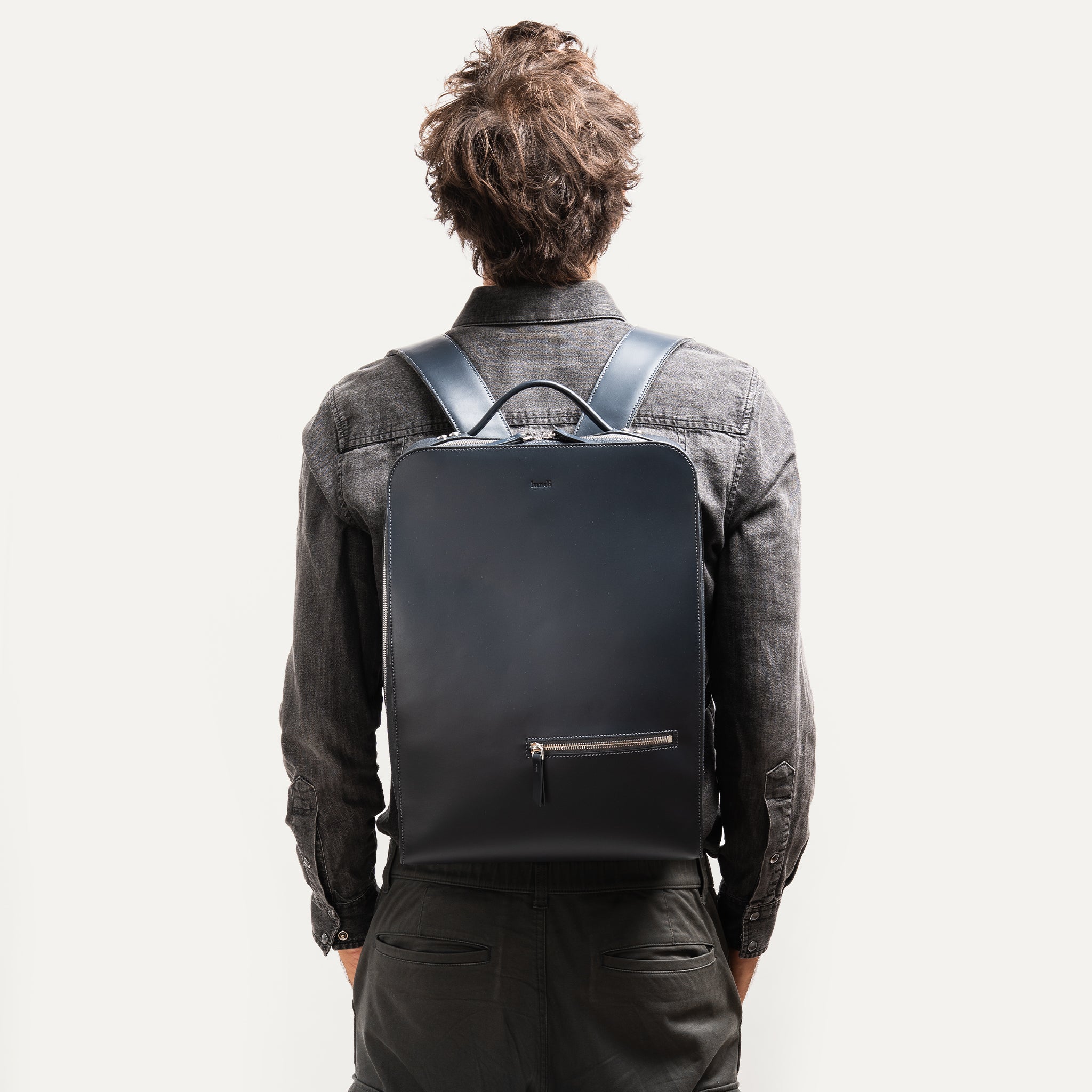 sac à dos homme en cuir porté avec un costume, parfait pour travailler avec un style business chic.