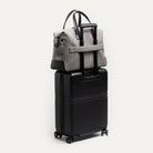 Sac de voyage cabine en toile grise et cuir noir, passant trolley intégré pour déplacements d’affaires.
