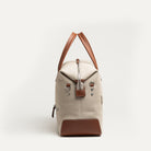 Sac de voyage pour homme en toile beige et cuir cognac, passant trolley intégré pour valise cabine.