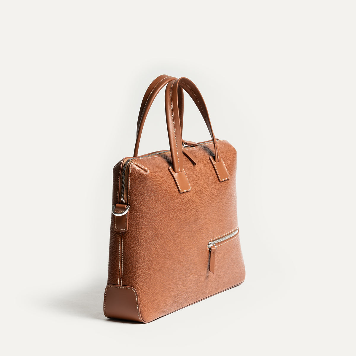 Sac à main homme en cuir camel, silhouette verticale raffinée et fonctionnelle.
