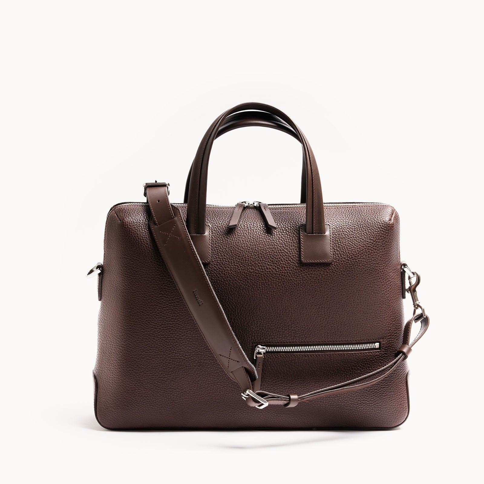 Porte document en cuir marron au design minimaliste avec bandoulière amovible, parfait pour un usage professionnel.