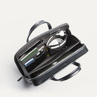 Attaché case lundi ouvert, montrant les multiples rangements pratiques pour ordinateur portable, câbles, carnet et accessoires.